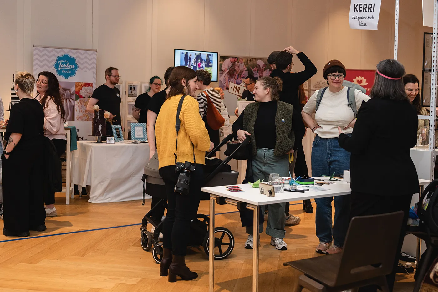 Besucher:innen im Gespräch zwischen den Messeständen
