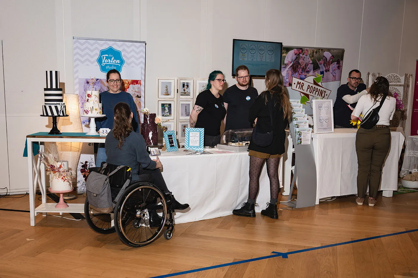 Besucherin im Rollstuhl am Stand des Tortenstudios mit Hochzeitstorten