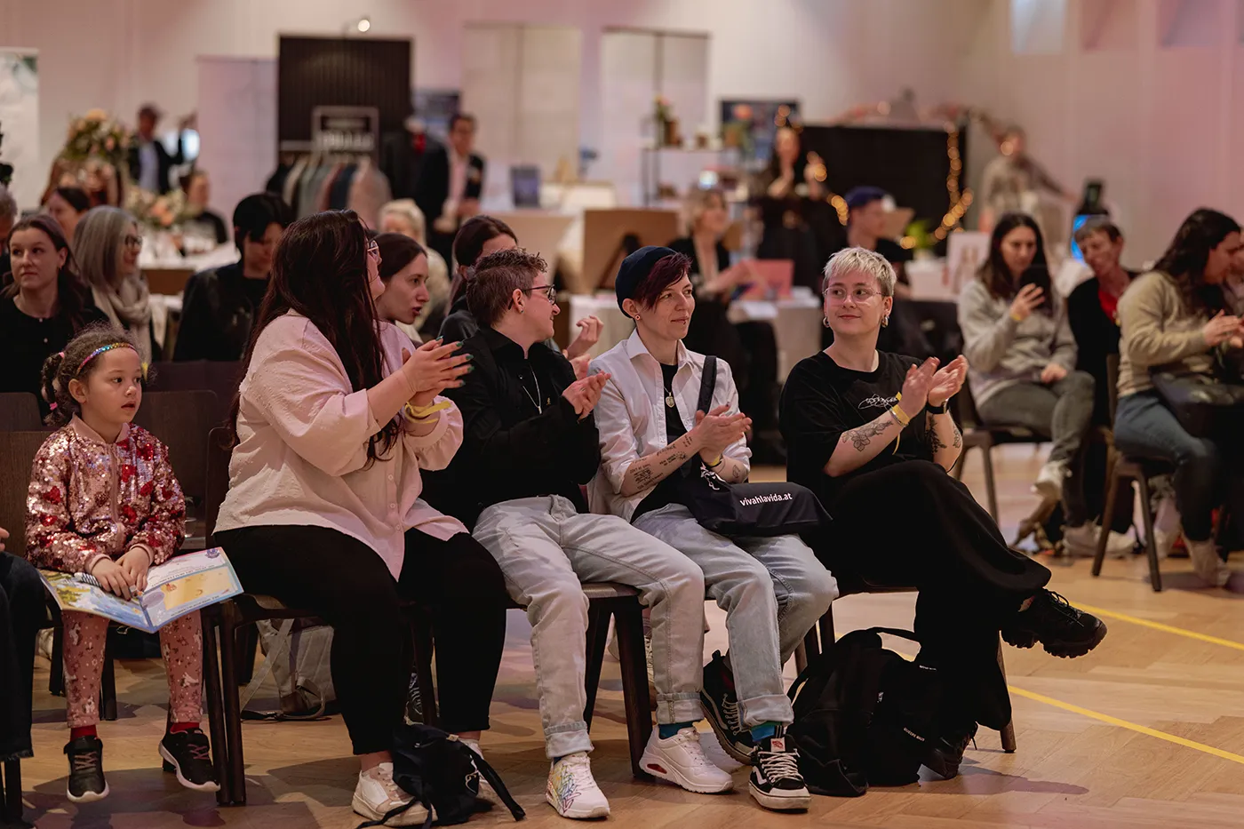 Publikum applaudiert beim Bühnenprogramm, im Vordergrund ein Kind