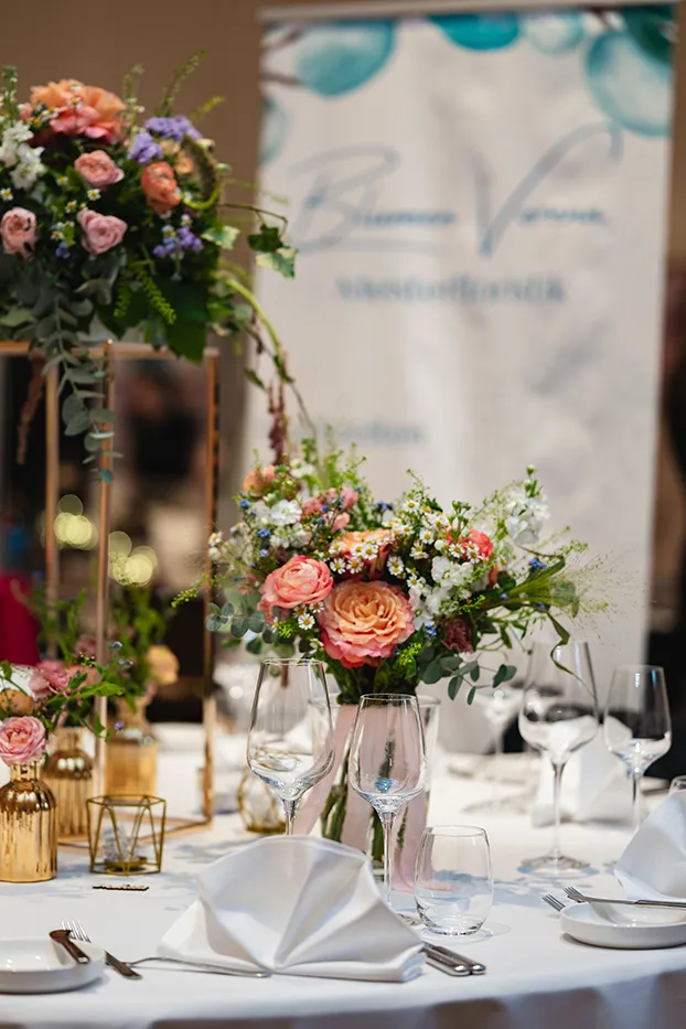 Festlich gedeckter Tisch mit Blumenschmuck an einem Messestand