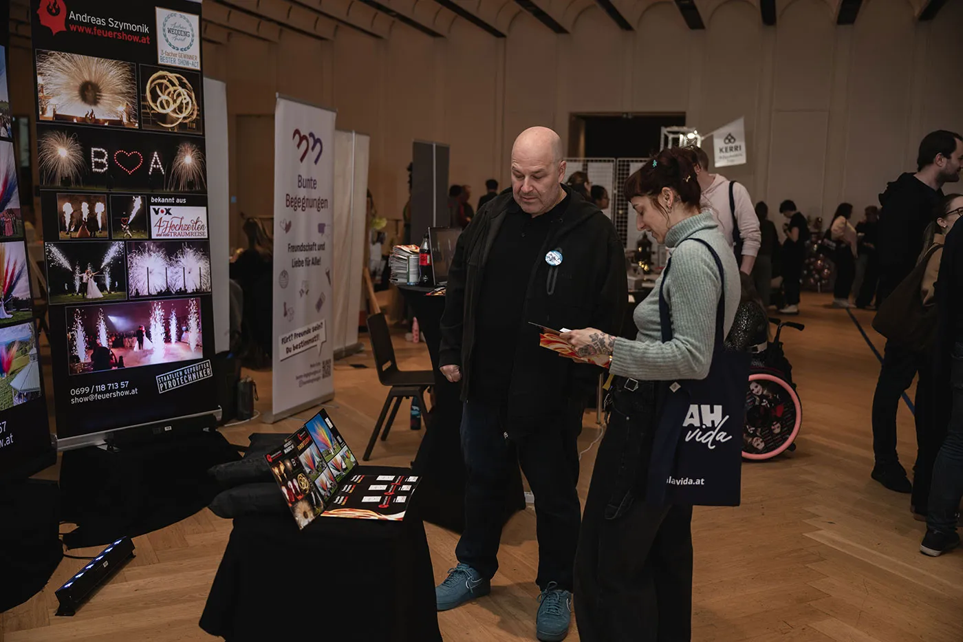 Besucher:innen am Stand mit Bildern einer Feuershow