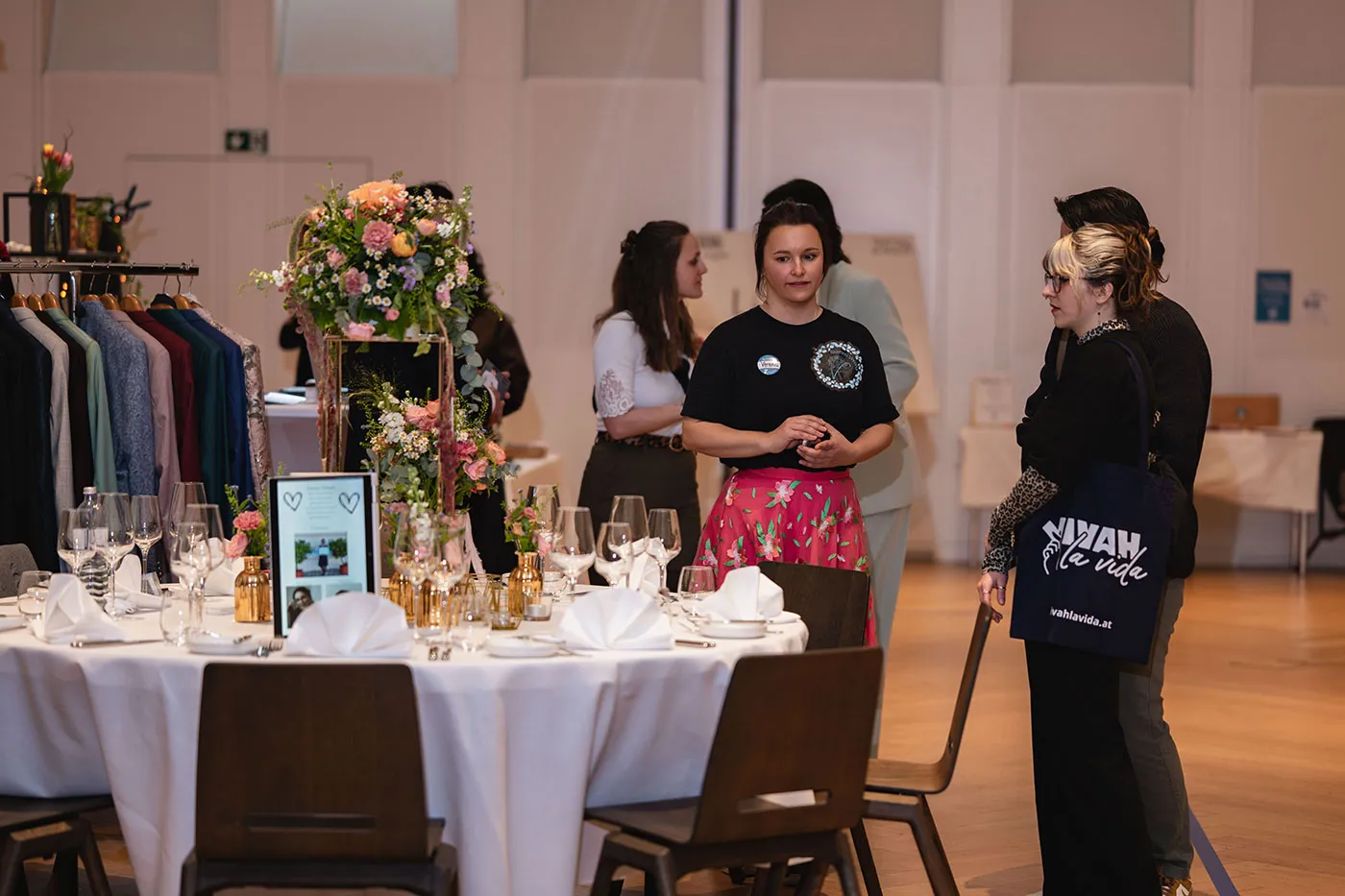 Ausstellerin im Gespräch an einem festlich gedeckten Tisch mit Blumenschmuck