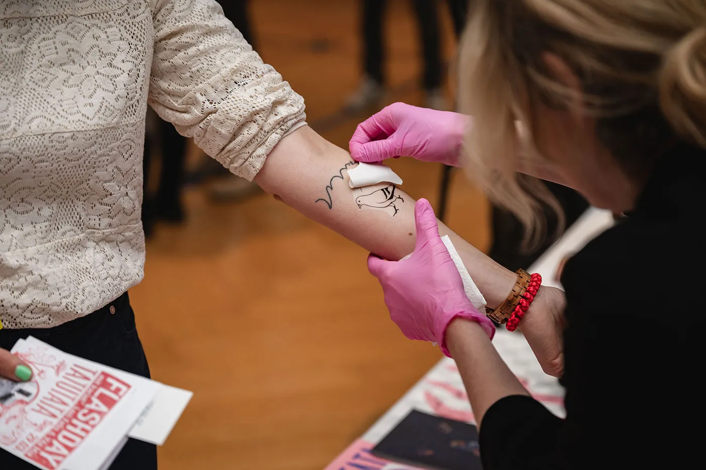 Klebetattoo wird auf den Arm einer Besucherin aufgetragen