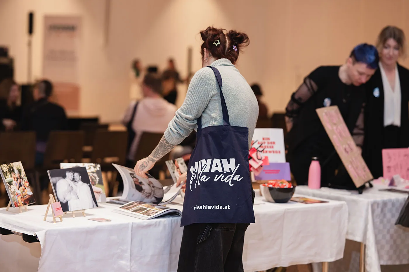 Besucherin mit Vivah la Vida Tasche stöbert an einem Messestand