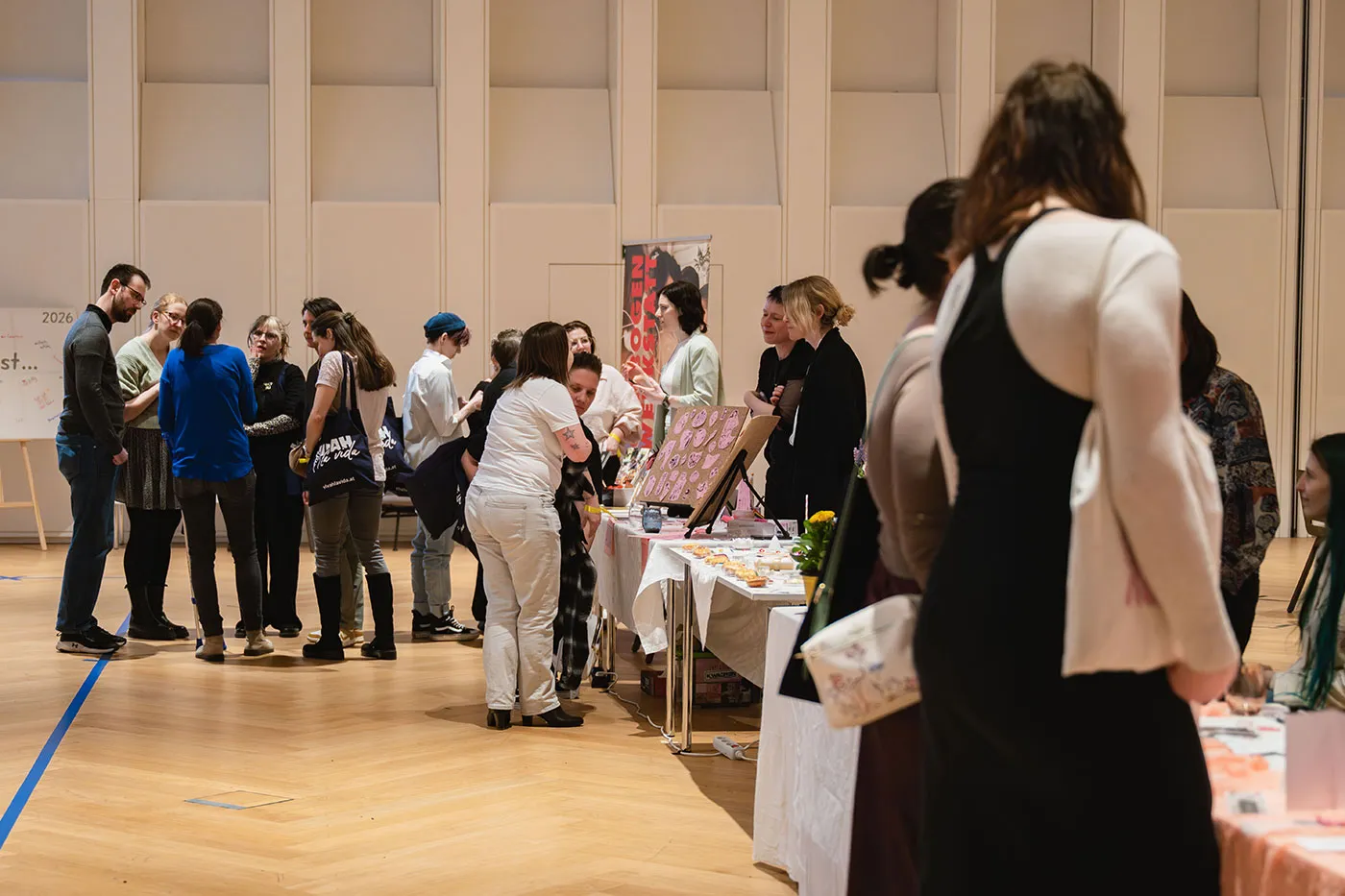 Blick über die Messehalle mit Besucher:innen an den Ständen