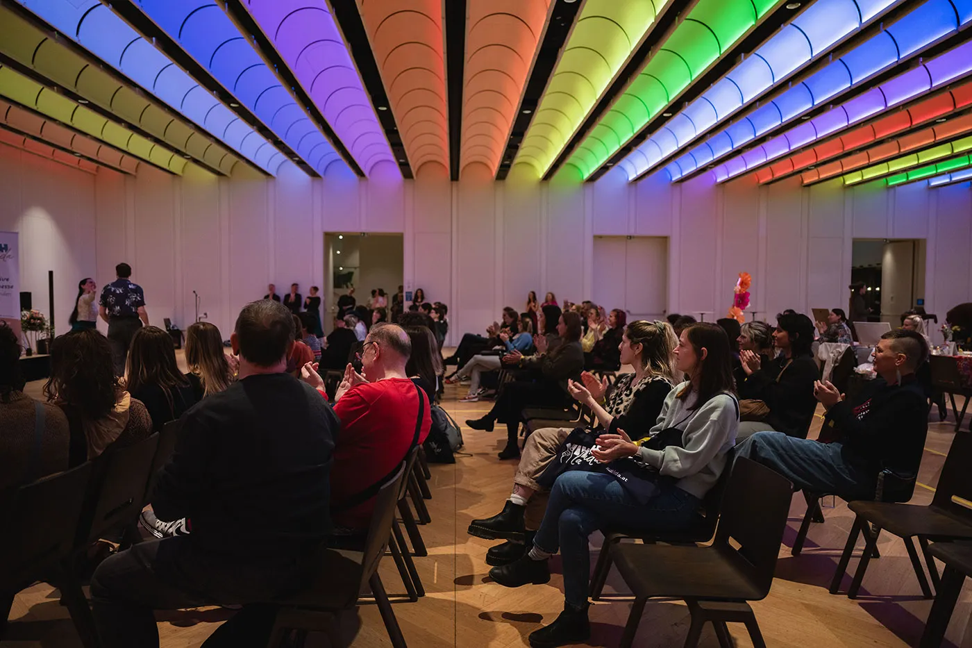 Publikum verfolgt das Bühnenprogramm unter der Regenbogenbeleuchtung
